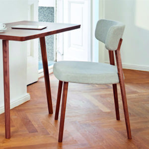 Marlon Dining Chair Stuhl mit breiter Rücken- und Sitzfläche in moderner dynamischer Form mit hellem Stoff überzogen und hellen Beinen aus Holz mit schlichtem Tisch