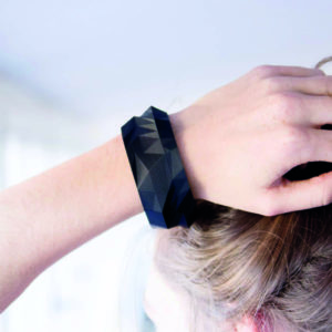 Poly bracelet made of geometric surfaces in dark plastic on the wrist of a person