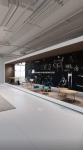Virtuelle Tour von Alexander Rehn Designstudio mit Stühlen, Tischen unt Tafel mit Skizzen im Hintergrund in großer industrieller Halle