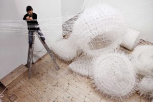 Person installs Third Space made of white woven cable ties with wild spiky structure