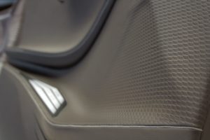 Car door interior trim of dynamic shapes covered in brown textured leather