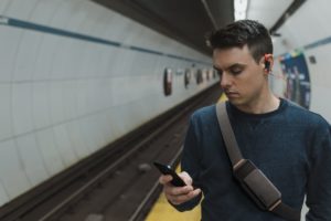 Nest of Galaxy carrying strap and case in a simple and geometric shape for carrying smartphones, worn crossbody by a person in a metro station