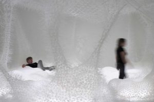 Third Space spatial installation made of white woven zip ties with wild spiky structure emerges pillows, columns and nets with persons