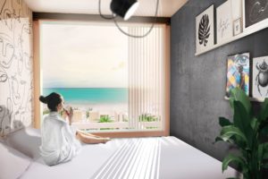 South Beach Lodge small room with large window overlooking Miami beach and large bed with woman sitting on it