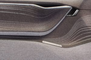Car door interior trim of dynamic shapes with armrest, door handle and adjustment panel covered with textured dark beige fabric