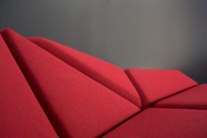 Cay Sofa with different geometric cushions turned in different directions and covered with red fabric