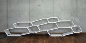 P13 Shelf system with differently sized cells as shelves in white in front of concrete wall