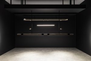 Pohlcon SystemPlus pendant luminaires with cooling fins hang from the ceiling in a dark room