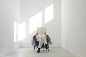 Person with book sits in Oricio chair made of interwoven zip ties with wild spiky texture in bright room