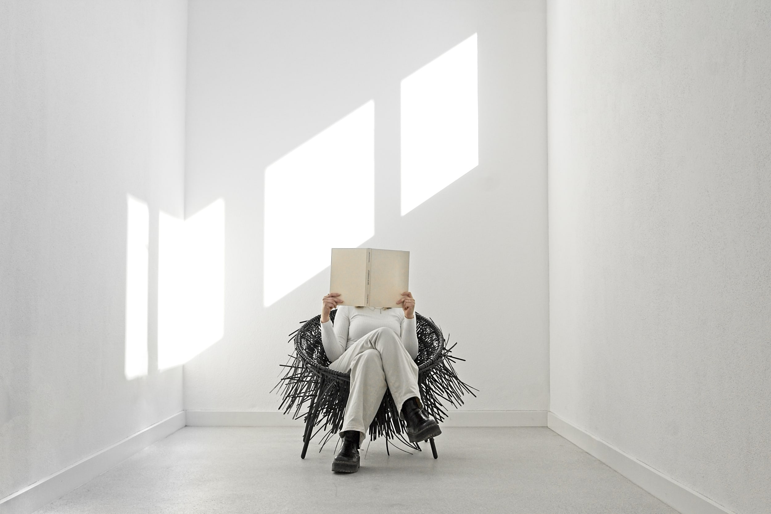 Person mit Buch sitzt im Oricio-Stuhl aus verflochtenen Kabelbindern in einem hellen Raum