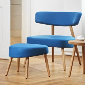 Marlon Lounge Chair with wide back and seat in modern dynamic shape covered with light blue fabric and light wooden legs with chair for footrest and side table with coffee cup
